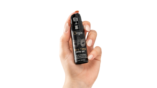Eine Hand hält eine kleine schwarze Sprühflasche mit Aufdruck "Orgie Ultra Time Delay Gel" und Pumpe.