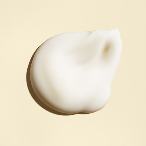 Ein Klump weiße Creme oder Lotion auf hellem Hintergrund mit weichen Schatten.