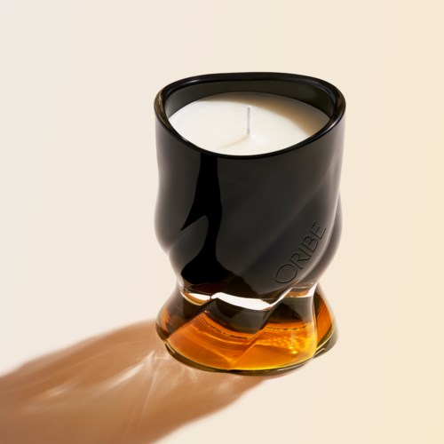 En svart och bärnfärgad ljuslykta av glas med ett vitt ljus inuti, som kastar en skugga på ytan.