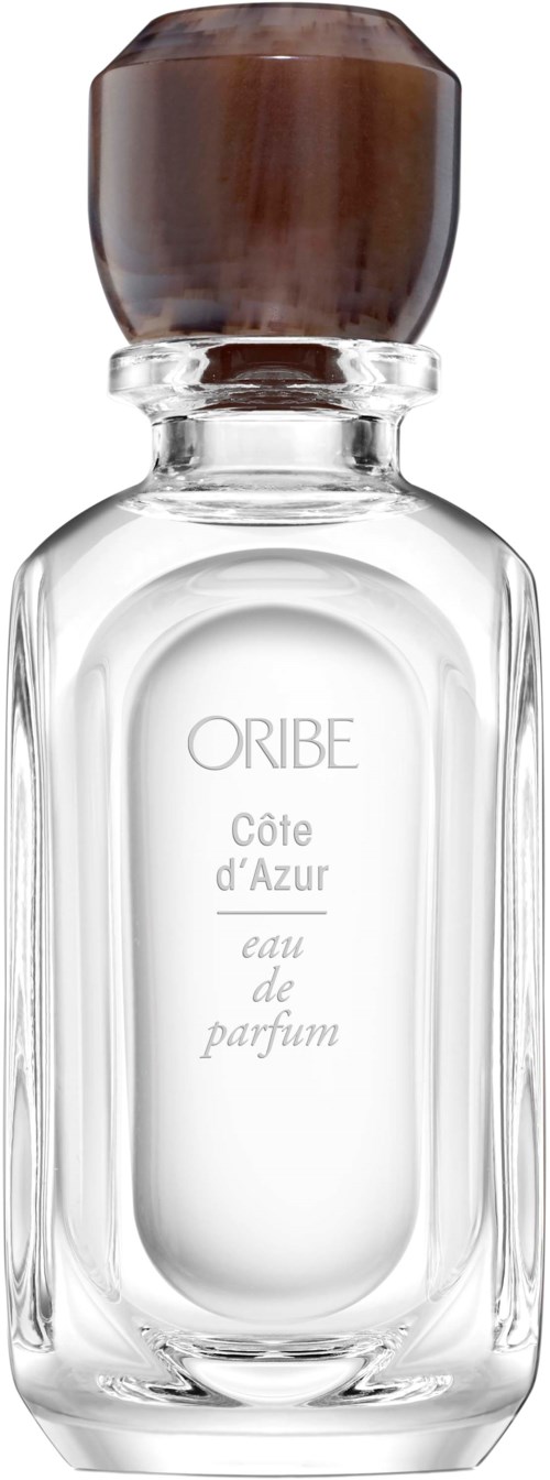 Eine transparente Parfümflasche mit braunem Deckel, beschriftet "ORIBE Côte d'Azur eau de parfum."