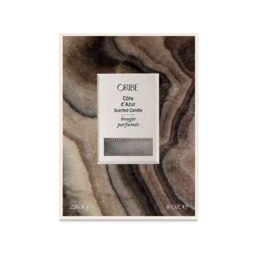 Eine Duftkerzenverpackung mit der Aufschrift "ORIBE Côte d'Azur" vor marmorartigem Hintergrund.