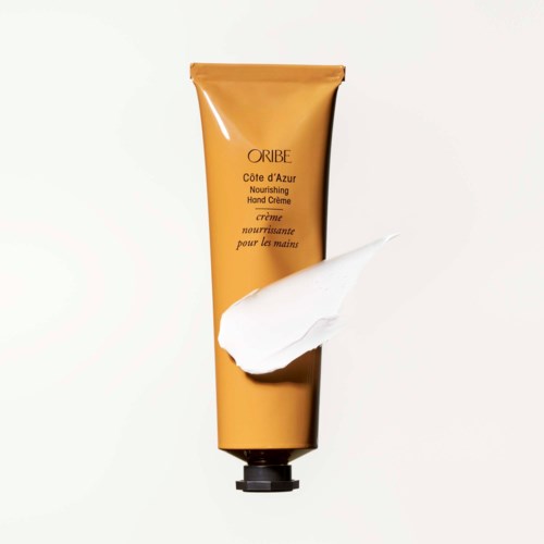 Eine gelbe Tube Handcreme mit einem weißen Klecks, beschriftet "Oribe Côte d'Azur".