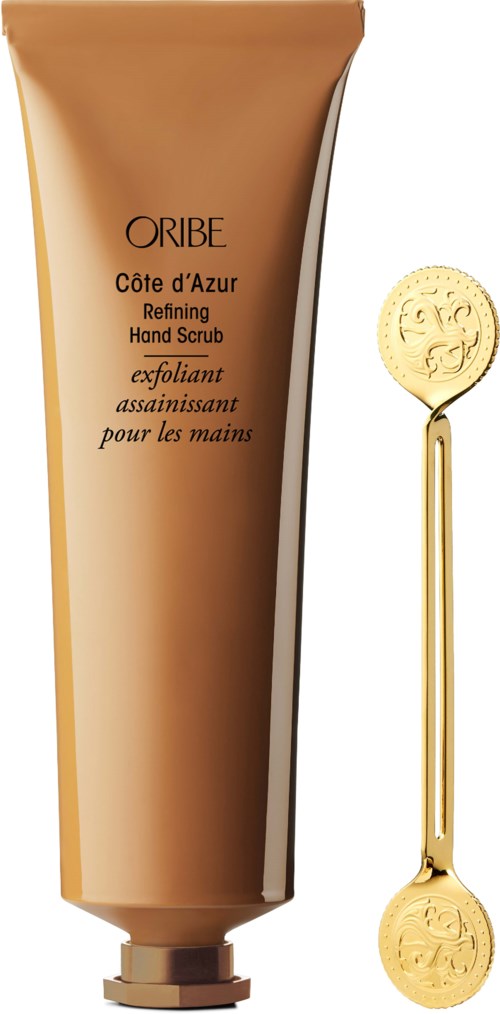 Eine Tube ORIBE Handpeeling mit einem goldenen Löffel daneben, beide mit goldenen Designs versehen.
