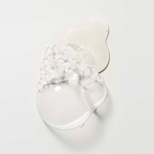 Ein klares Gel mit weißer Creme und Blasen, geformt wie eine abstrakte Blume auf weißem Hintergrund.