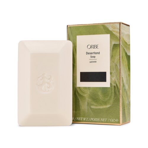 Ein Seifenstück mit einer Schachtel daneben mit der Aufschrift "Oribe Desertland Soap" und einem dekorativen Design.