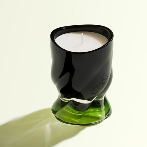 Ein schwarzer und grüner Kerzenhalter mit einer weißen Kerze, die einen Schatten auf hellen Hintergrund wirft.