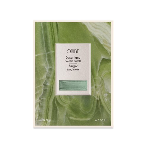 A scented candle package with a green marble design and reading 'Oribe Desertland.'