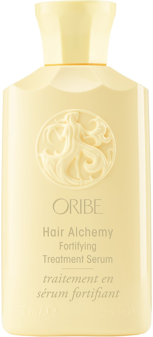A cream-colored bottle with a round logo of a woman and flowing hair, labeled "ORIBE Hair Alchemy Fortifying Treatment Serum."
