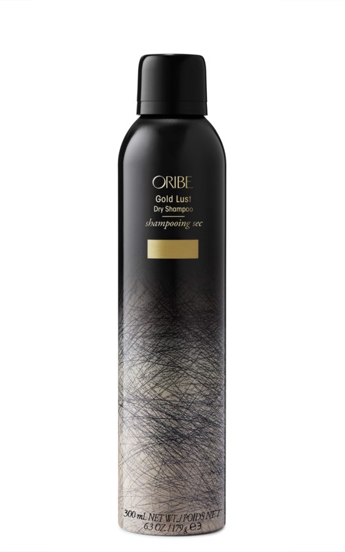 Svart sjamponflaske med gullmerke, merket 'ORIBE Gold Lust Dry Shampoo,' og et teksturert sølv- og svart design.