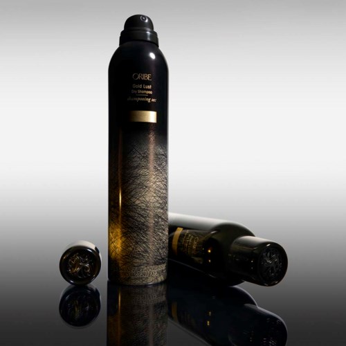Eine schwarze Flasche und zwei Deckel sind auf einer reflektierenden Oberfläche, mit gold- und schwarzen Designelementen.