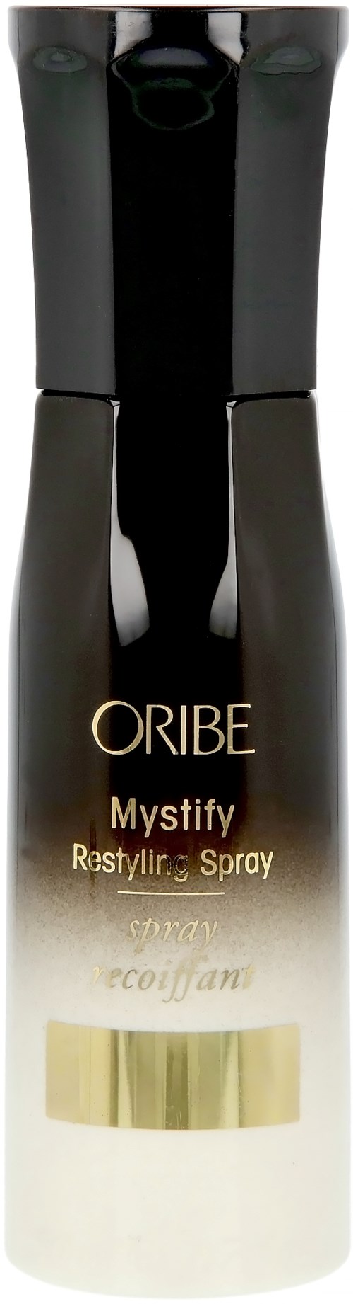 Schwarz-weiße Flasche mit goldener und brauner Schrift, gekennzeichnet als Oribe Mystify Styling Spray, steht aufrecht.