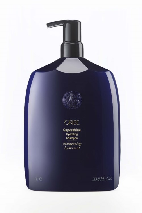 Eine dunkle blaue Shampooflasche mit schwarzem Pumpaufsatz, beschriftet Oribe Supershine Hydrating Shampoo.