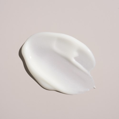 Eine weiße, gebogene Portion Creme oder Lotion auf hellem Hintergrund.