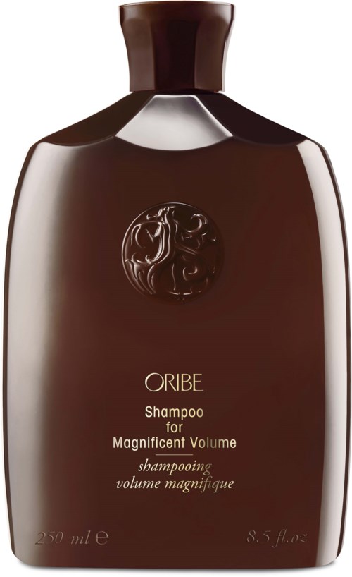 Een bruin shampoo fles met een zwarte dop, met tekst die aangeeft dat het volume geeft, met een decoratief embleem.