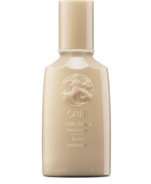 Eine beigen, ovalförmige Lotionflasche mit Deckel, beschriftet als Oribe Matte Waves Texture Lotion.