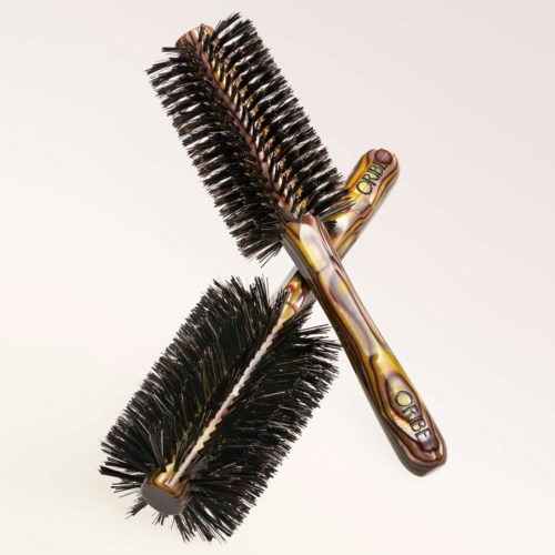 Two round, bristle brushes with patterned handles cross each other on a plain background.
