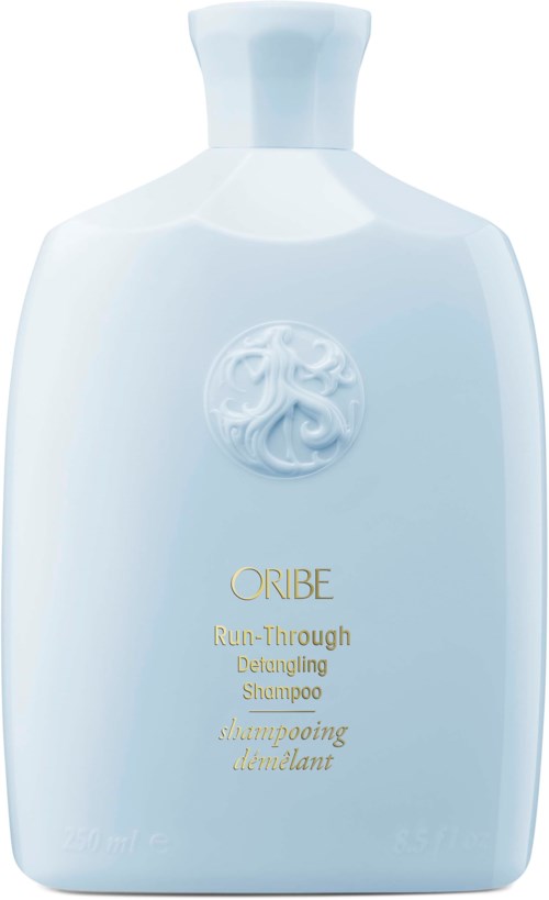 Lichtblauwe fles met Oribe Run-Through Detangling Shampoo met gouden tekst en logo.