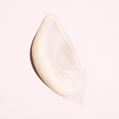Ein Klecks weiße Creme oder Lotion auf hellrosa Hintergrund.