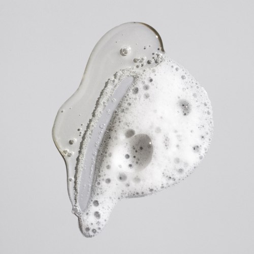 Eine transparente Seifenblase mit Schaum im Inneren auf hellem Hintergrund.