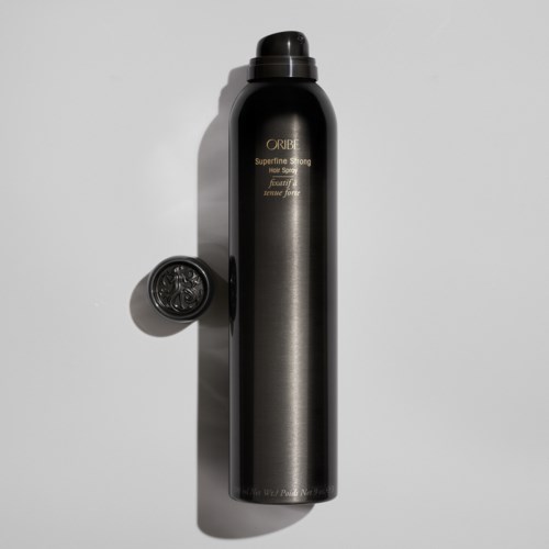 Eine lange schwarze Haarspraydose mit Deckel, beschriftet mit "Oribe" und "Superfine Strong" auf weißem Hintergrund.