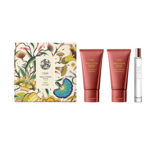 Ein Geschenkset mit Blumenmuster, bestehend aus zwei roten Tuben und einer kleinen weißen Flasche. Wahrscheinlich Hautpflege oder Parfüm.