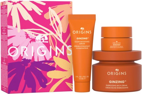 Orangenflaschen und eine Box mit rosa, lila und gelben Blumenmuster. Die Produkte sind Hautpflege- oder Schönheitsartikel.