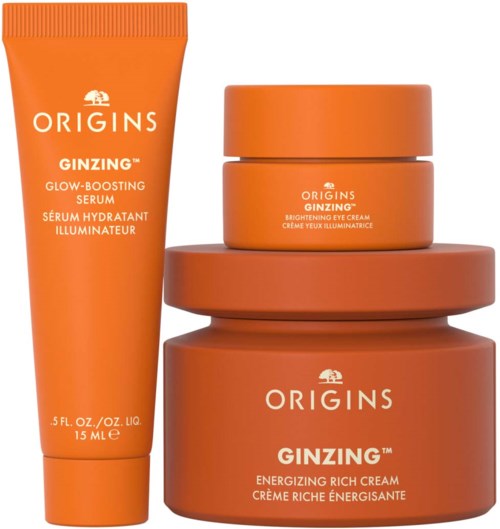 Ein Satz Hautpflegeprodukte in orange Behältern, darunter eine Tube, eine kleine Dose und zwei größere Dosen. Text sagt Origins Ginzing.