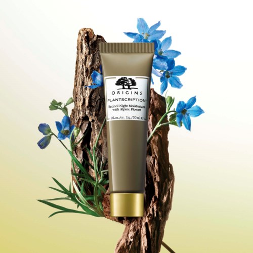 Eine Tube von Origins mit blauen Blumen und Holz, bewirbt einen nächtlichen Feuchtigkeitscreme mit Alpenblume.