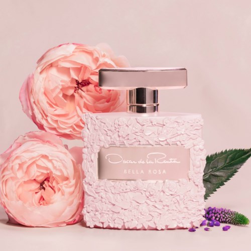 En rosa doftflaska med silverlock, omgiven av rosa rosor, ett grönt blad och små lila blommor.