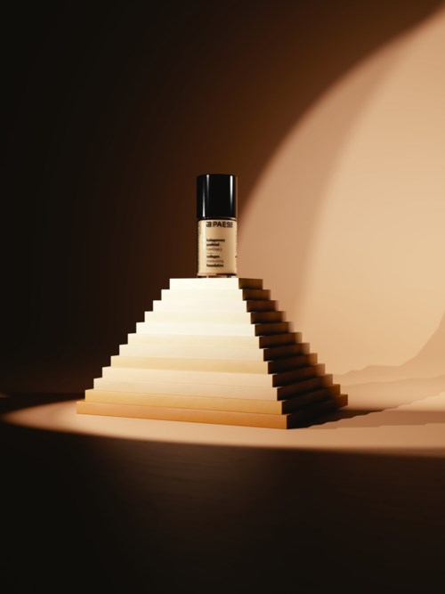 A makeup bottle on a pyramid staircase with a light and dark background. The bottle is centered and lit.