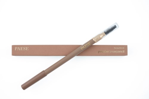 A beige eyebrow pencil with a spoolie brush, lying on top of a pink box. The box has text on it.