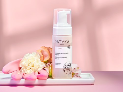 Eine rosa-weiße Flasche von Patyka Detox-Reinigungsschaum mit Blumen auf einer Schale.