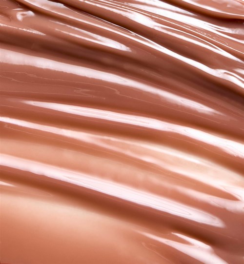 Närbild av en rosa-beige krämig texturerad yta, troligen ett skönhets- eller kosmetikaprodukt som foundation eller lotion.