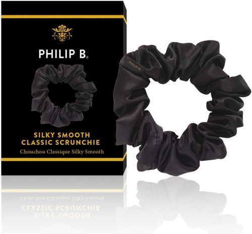 En svart boks med gull-tekst og logo, ved siden av en svart silkeaktig hårstrikk. Produktnavnet viser "Silky Smooth Classic Scrunchie."