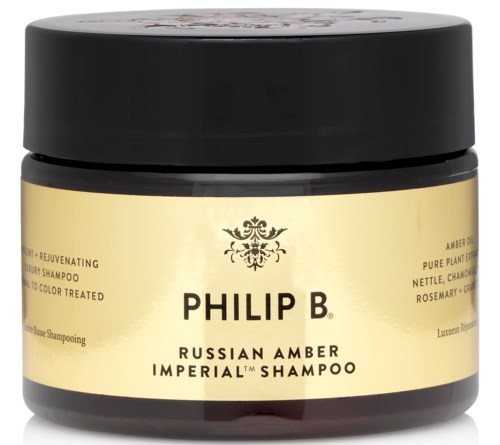 Ein dunkler Behälter mit gelber Etikette für Philip B Russian Amber Imperial-Shampoo, das als verjüngend und für farbbehandeltes Haar beschrieben wird.