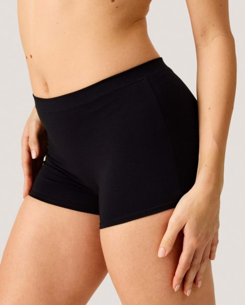 Eine Frau trägt schwarze Shorts in einer Nahaufnahme, zeigt Taille und obere Oberschenkel.