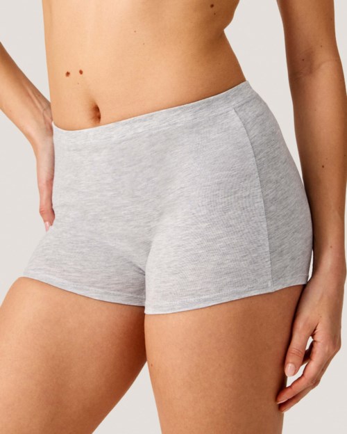 Graue Shorts an einer Person mit flachem Bauch, steht mit den Händen an den Seiten.