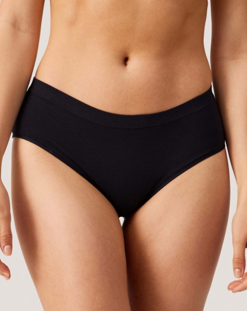 Eine Frau trägt schwarze Unterwäsche, Fokus auf Hüften und Taille.