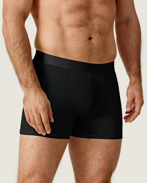 Ein Mann trägt schwarze Boxershorts, zeigt seinen Oberkörper und Oberschenkel.