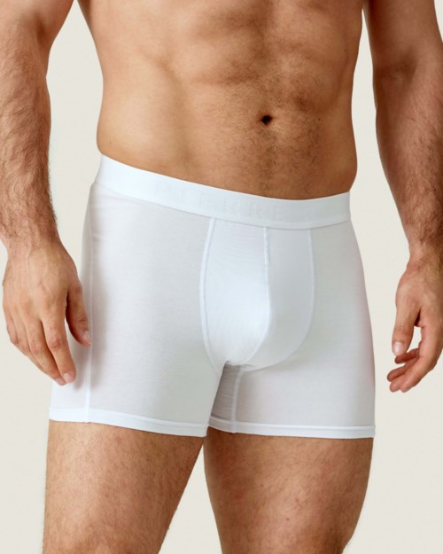 Ein Mann trägt weiße Boxershorts, zeigt seine Oberschenkel und Bauch.