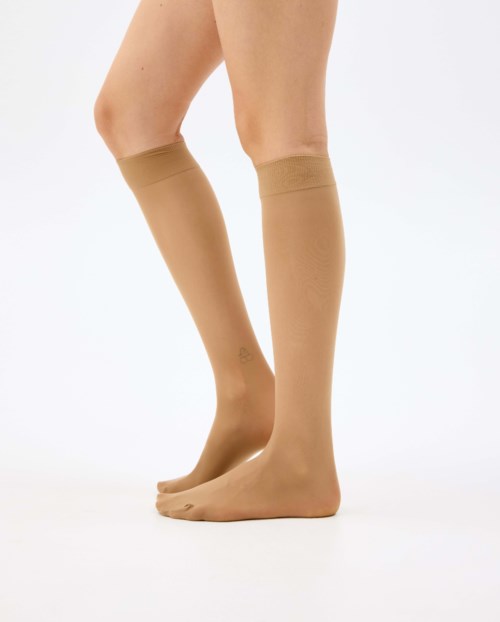 Beige knestrømper på ben mot hvit bakgrunn.