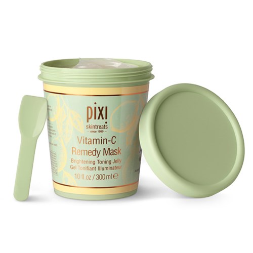 Ein Behälter mit Pixi Vitamin C Remedy Maske und Spatel, vor einfachem Hintergrund.