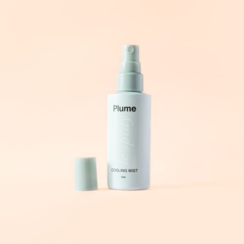 Eine weiße Sprühflasche mit der Aufschrift 'Plume' und abgenommenem Deckel vor einem hell pfirsichfarbenen Hintergrund.