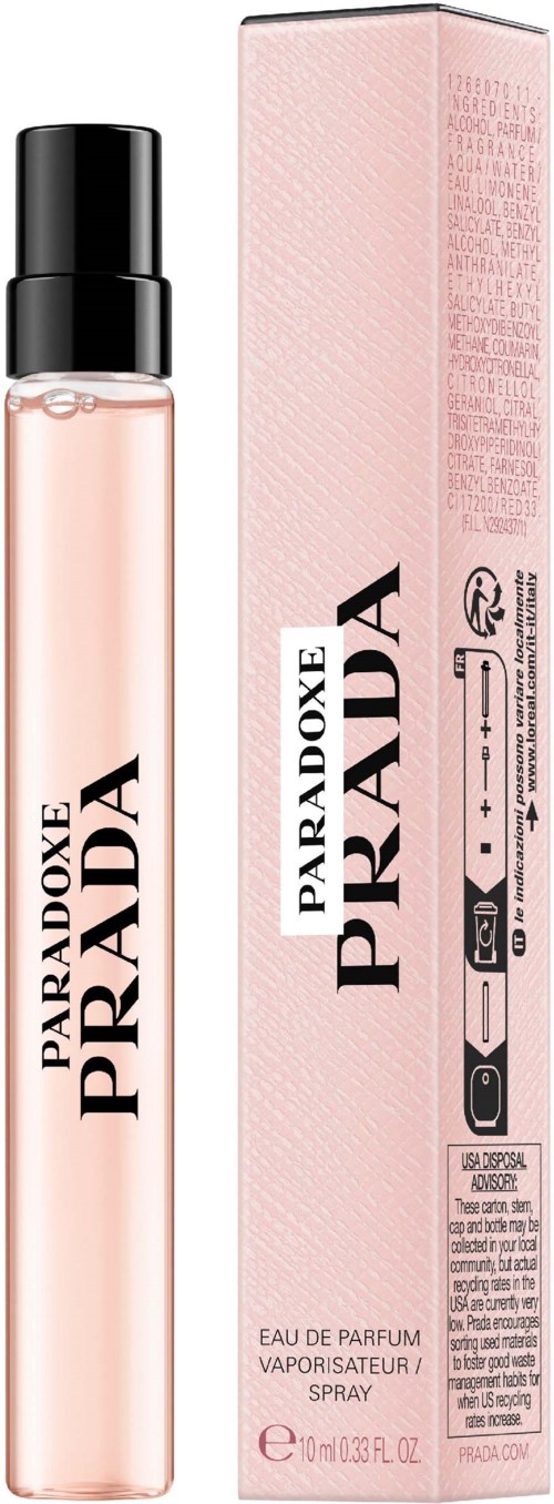 En parfymflaska med rosa vätska och svart lock bredvid dess rosa förpackning, märkt "Paradoxe Prada."