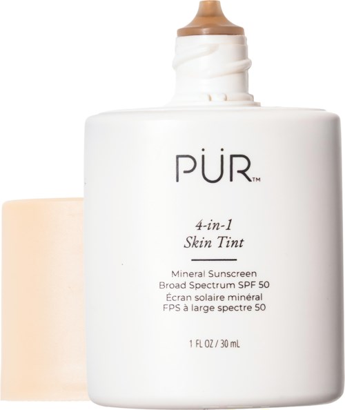 Valkoinen pullo PÜR 4-in-1 Skin Tint SPF 50, vieressä beigen sieniharja.