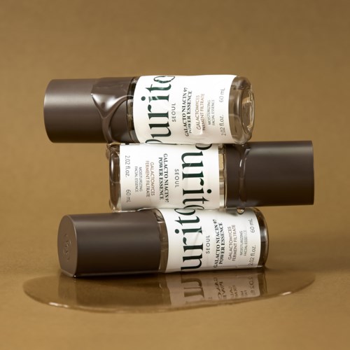 Drie flesjes nagellak horizontaal gerangschikt, met donkere doppen en witte labels, die licht reflecteren.