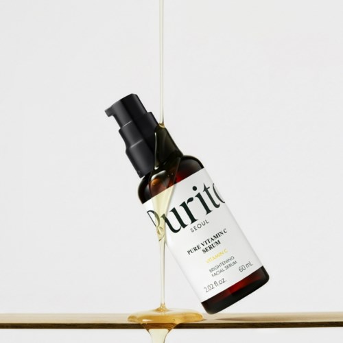 Een bruin flesje met Purito-label, serum stroomt eruit en ligt schuin op een oppervlak.
