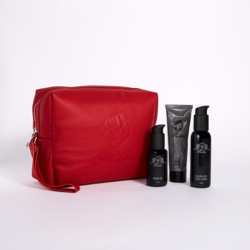 A red toiletry bag with three black bottles and a small gray tube in front on a white background.