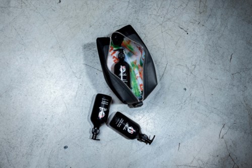 A bag open with colorful clothes inside, two small bottles outside on a grey surface.