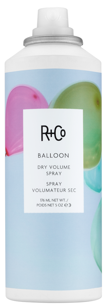 En hvit sprayflaske med fargerike ballongbilder og en etikett som sier R+Co Balloon for tørr volum.